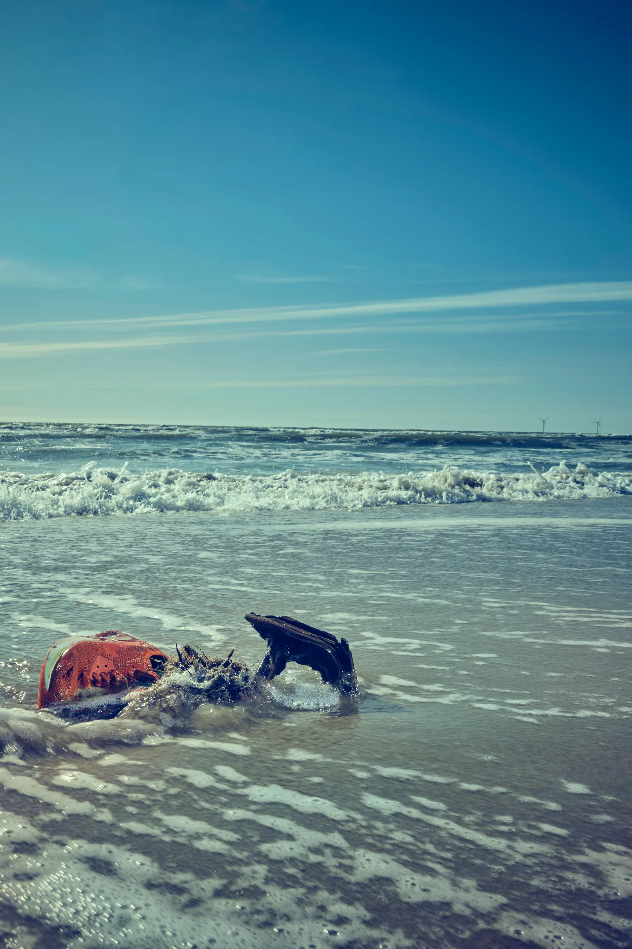 Sko og affald skyllet op på stranden ved havkanten